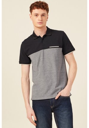 Zwarte en grijze polo shirt met een effen bovenstuk en een gestructureerd onderstuk, voorzien van een kleine borstzak en contrasterende afwerking.