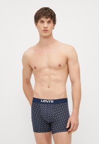 Námorníckomodré trenky Levi's s geometrickým bielym vzorom, s pevným pásom s logom Levi's. Vyrobené z príjemného materiálu.