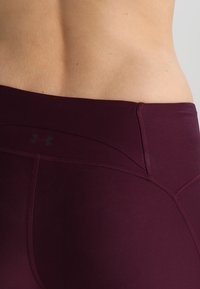 Leggings bordeaux a vita alta con una texture liscia e stretchy e cuciture flatlock. Presenta un logo sottile sulla vita e cuciture sagomate.