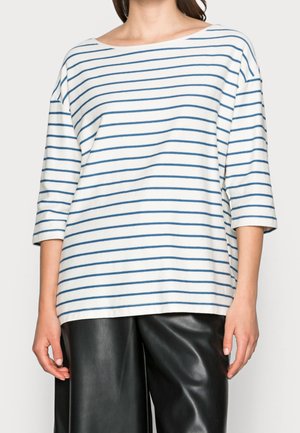 White striped shirt with blue horizontal lines, boat neckline, and three-quarter sleeves. Paired with black leather pants.