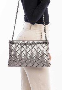 Srebrna torebka pleciona z teksturowym wykończeniem, z łańcuszkowym paskiem i prostokątnym kształtem. Gładki materiał z plecionym wzorem.