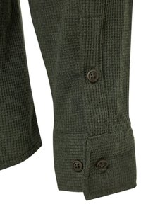 Poignet de chemise à manches longues en maille gaufrée vert foncé avec deux boutons et un détail de patte de manche boutonnée.