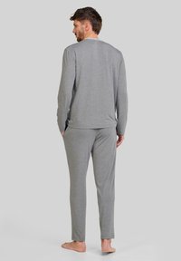 Conjunto de camiseta de manga larga y pantalones grises hechos de una tela suave. La camiseta tiene un cuello redondo y los pantalones tienen un corte recto sin bolsillos.