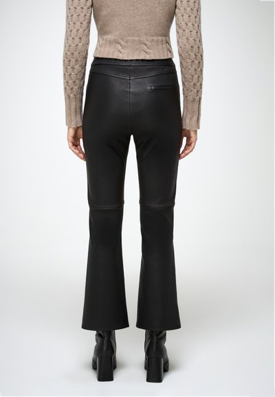 Pantalones de campana negros hechos de un material similar al cuero, con una cintura ajustada y un sutil detalle de costura en la parte posterior.