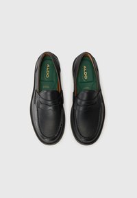 Zwarte leren instappers met een slip-on ontwerp, voorzien van decoratieve stiksels en een ronde neus. Groene binnenzolen met gouden branding.