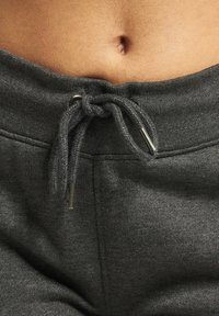 Pantalons de survêtement en coton gris avec fermeture à cordon de serrage. Présente une texture douce et des accents métalliques aux extrémités du cordon.