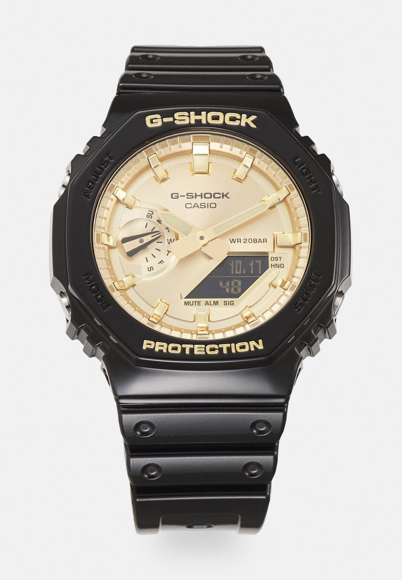 Orologio G-Shock con cinturino in resina nera, quadrante analogico e digitale dorato, lunetta testurizzata e i prominenti marchi "PROTECTION" e "G-SHOCK".