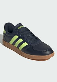 Navy leather sneakers with three lime green stripes, textured rubber sole, and padded collar. Features perforations for breathability.