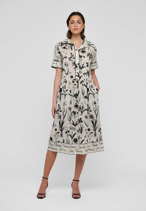 Kleid mit Blumenmuster in hellem Beige mit schwarzen Designs, kurzen Ärmeln, Kragen, Knopfleiste vorne und seitlichen Taschen. Glatter Stoff.