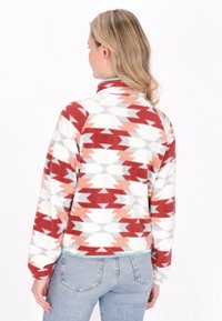 Fleece pulóver piros, őszibarack és szürke geometrikus mintával. Magas gallér, hosszú ujjú, elasztikus mandzsetta, és türkiz dísz a szegélyén.