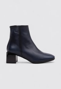 Bota de tobillo de cuero azul marino con punta afilada y tacón grueso negro. Textura suave, diseño minimalista y silueta elegante.