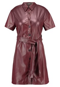 Kurzarm, kurzärmliges Hemdkleid aus burgunderfarbenem Kunstleder, mit einem taillierten Gürtel und einer glatten, glänzenden Oberfläche. Schwarze Knöpfe an der Vorderseite.