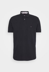 Polo de color azul marino hecho de algodón, con un collar clásico, tapeta de dos botones y un pequeño logotipo en el pecho.