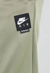 Nærbillede af et lys grønt stof med et sort Nike Air logo-patch syet på, der har den hvide Nike swoosh og teksten "NIKE AIR."