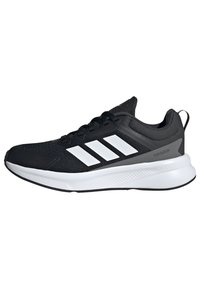 Chaussure de sport noire avec dessus en maille, trois rayures blanches sur le côté et une semelle blanche rembourrée. Bout et talon renforcés.