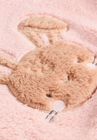 Weiche rosa Decke mit einem Hasengesicht-Applikation aus plüschigem, beige Stoff, mit gestickten Details und einer flauschigen Textur.