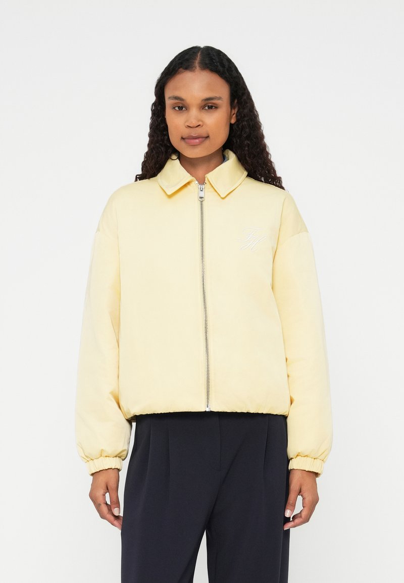 Dzeltena polsterēta bomberjakete ar rāvējslēdzēju, ribotām piedurknēm un apkakli. Uz krūtīm ir izšūts logs. Gluda tekstūra.