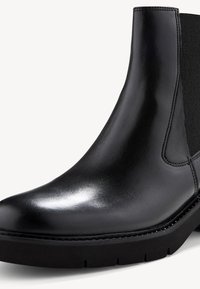 Black leather ankle boot with elastic side panel, smooth finish, rounded toe, and a thick rubber sole featuring prominent tread patterns.