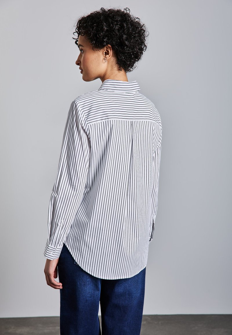 Camicia a righe bianca e navy con maniche lunghe, colletto e orlo curvo con uno spacco sul retro.