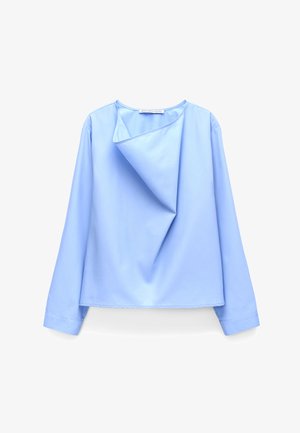 Hellblaue Langarmbluse mit asymmetrischem, gefaltetem Ausschnittdetail aus glattem Stoff, vor weißem Hintergrund dargestellt.