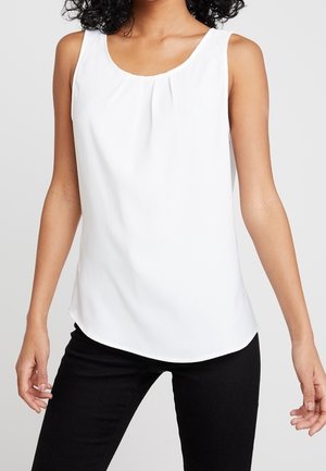 Haut blanc sans manches avec un col en V arrondi, présentant de subtiles plis à l'avant et un ourlet légèrement arrondi. Tissu lisse avec une sensation de légèreté.