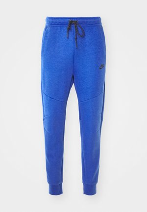 Blaue Nike-Sweatpants aus strukturiertem Stoff, mit schmal zulaufenden Beinen, elastischem Bund, Kordelzug und Seitentaschen. Schwarzes Logo-Highlight.