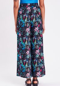 Black wide-leg pants with a vibrant floral and parrot pattern in pink, green, and blue. Elastic waistband for comfort and ease.