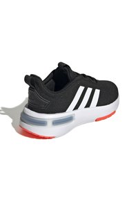 Černá sportovní bota s bílými pruhy, síťovaným svrškem, polstrovaným límcem, průhlednými detaily odpružení a kontrastní červenou podešví.