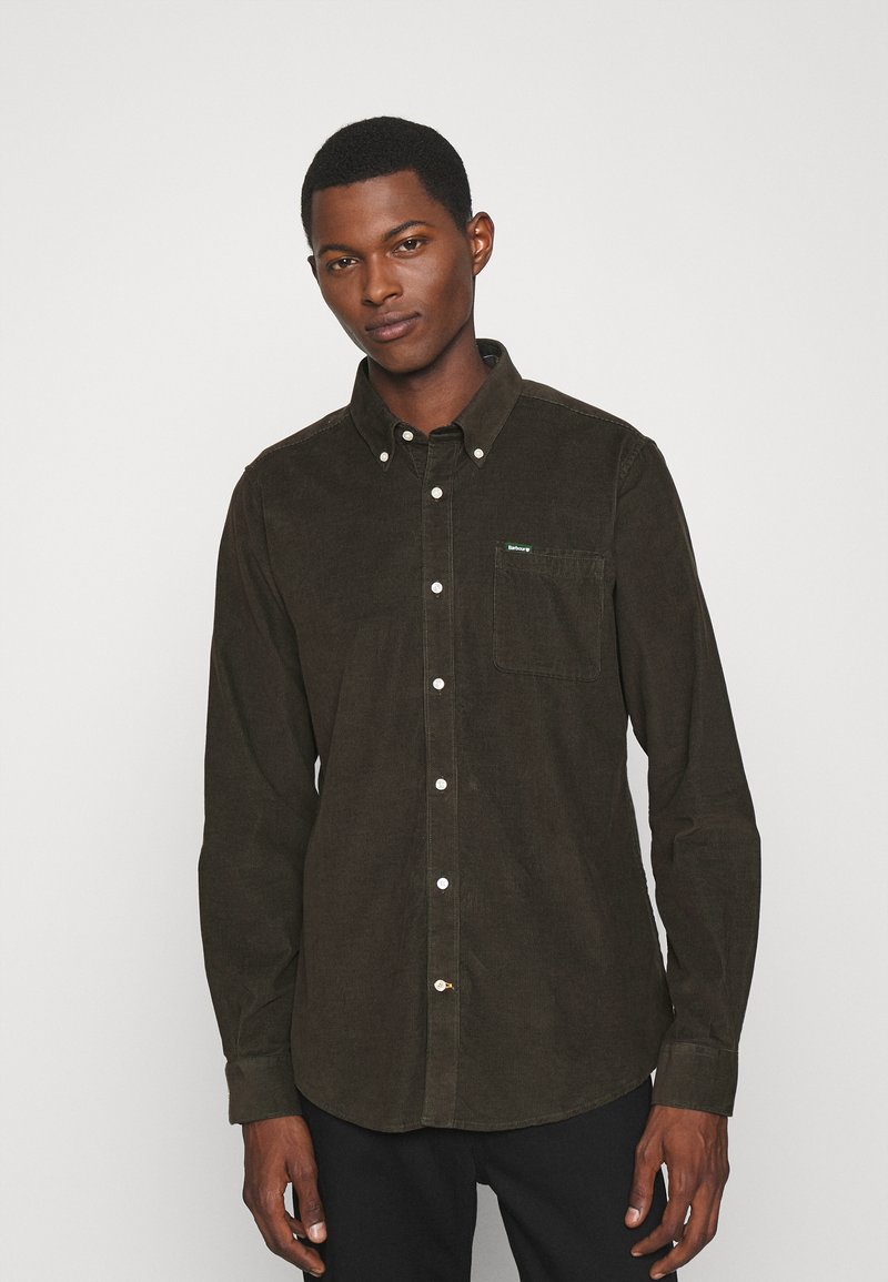 Bruine corduroy button-up shirt met een puntige kraag, borstzak en witte knopen. Heeft een klein groen logo op de zak.