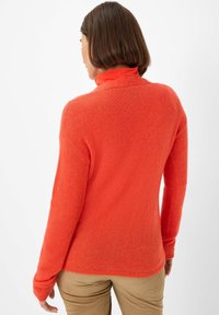 Oranges, gestrickter Rollkragenpullover mit langen Ärmeln; weiche Textur; taillierter Schnitt; scheint ein leichtes, gemütliches Kleidungsstück zu sein.