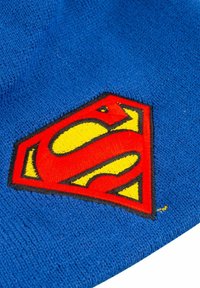 Blaues Baumwollstrickmütze mit einem großen, gestickten roten und gelben Superman-Logo auf einem diamantenförmigen Hintergrund.