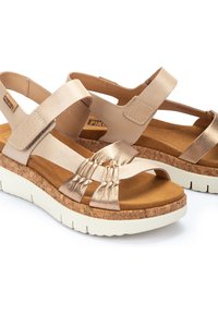 Sandali in pelle con suola in sughero, dotati di cinturini beige e metallici, punta aperta e soletta sagomata per il massimo comfort.
