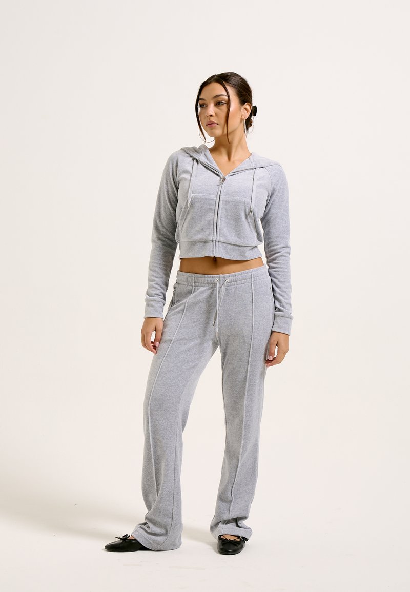 Hoodie cinza com capuz, com fecho na frente e cordão, combinado com calças de moletom cinzas a condizer, com costuras laterais e um corte descontraído.