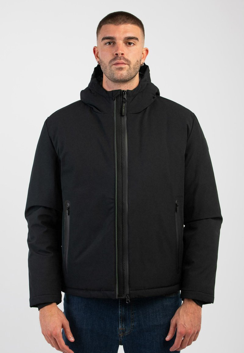 Schwarze gepolsterte Jacke mit Kapuze, ausgestattet mit einem frontalen Reißverschluss und zwei Reißverschlusstaschen. Das Material ist glatt mit einer matten Oberfläche.