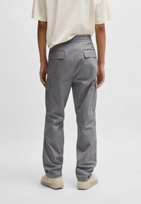 Grå cargo bukser med elastisk talje; har to sidelommer og en glat tekstur. Kombinationen med en lysefarvet t-shirt og beige sko.