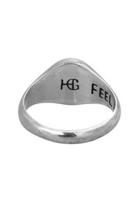 Silver ring med en avsmalnande form, slät yta och graverad text på insidan. Texten lyder "HG FEEL."