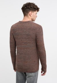 Pulover tricotat în nuanțe de maroniu și gri, având un guler rotund, mâneci lungi și un model texturat. Purtați-l cu blugi gri.