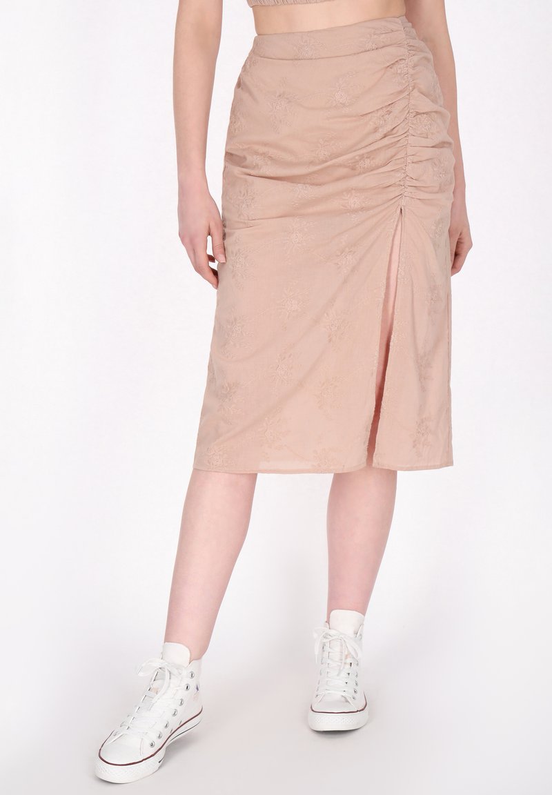Beige midi rok met geplooide textuur, bloemenpatroon, zijsplit en zachte stof. Gecombineerd met witte hoge sneakers.
