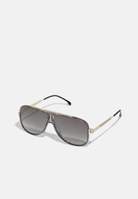 Ochelari de soare supradimensionați cu nuanță gri, cadru transparent, accente aurii și vârfuri negre pentru brațele ochelarilor. Prezintă un design de tip aviator.