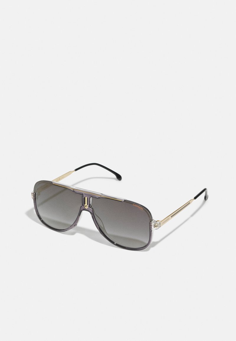 Ochelari de soare supradimensionați cu nuanță gri, cadru transparent, accente aurii și vârfuri negre pentru brațele ochelarilor. Prezintă un design de tip aviator.
