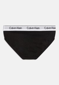 Čierne bavlnené slipy s bielym elastickým pásom, na ktorom je opakovane uvedený text "Calvin Klein". Hladká textúra a prispôsobený strih.