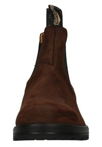 Stivaletto in suede marrone con pannelli elastici ai lati, tacco leggero e suola testurizzata. Presenta un cordoncino sul retro per una vestibilità facile.