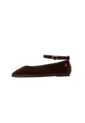 Zapato plano de terciopelo marrón oscuro con puntera afilada, correa en el tobillo con hebilla y pequeño logo de calavera y huesos cruzados cerca del talón.