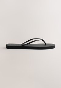 Tongs en caoutchouc noir avec semelle texturée et fines brides en forme de V, vues de côté sur un fond neutre uni.