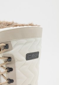 Beige insulated boot with chevron pattern, faux fur collar, black hardware, and beige laces. CMP logo on side. Smooth fabric texture.