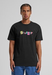 Černé bavlněné tričko s barevným grafickým potiskem "homeboy" v mixu blokových barev. Krátké rukávy a design s kulatým výstřihem v uvolněném střihu.