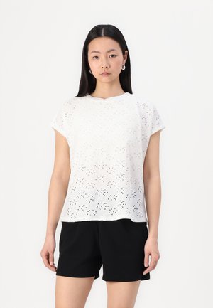 White short-sleeve top featuring a perforated pattern, round neckline, and relaxed fit, paired with black shorts. Smooth fabric texture.