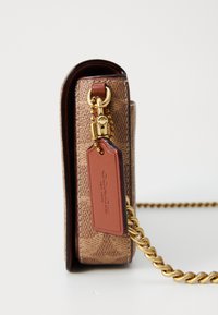 Braune Leder-Crossbody-Tasche mit strukturiertem Muster, goldener Kettenriemen und einem braunen Etikett mit dem Coach-Logo.