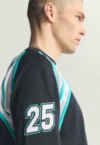 Czarna atletka z turkusowymi akcentami, siateczkową teksturą i białym numerem "25" na rękawie. Posiada okrągły dekolt i sportowy krój.