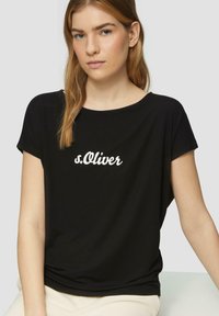 Zwarte T-shirt met korte mouwen, gemaakt van gladde stof, met een witte "s.Oliver" logo gecentreerd op de voorkant en een ontspannen pasvorm ontwerp.